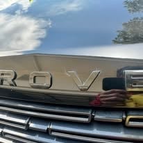 Close-up of a Ford truck hood and grille with blue sky and clouds in the background
