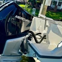 Outboard boat motor mounted on stern of white recreational boat at dock